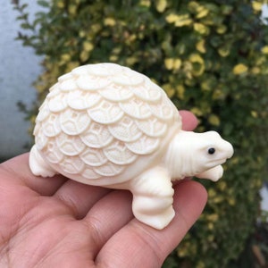 Peut inclure: Une petite figurine de tortue sculptée en blanc avec des détails sur la carapace et la tête.