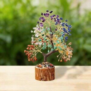 May include: A decorative tree sculpture with a brown trunk and branches made of gold-colored wire. The tree's leaves are colorful gemstones in shades of red, orange, yellow, green, blue, and purple. The base is a wooden block.