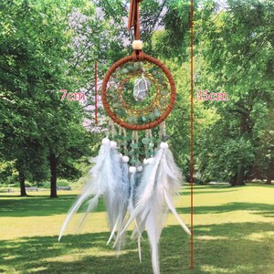 May include: A white feather dreamcatcher with green stones and a crystal charm. The dreamcatcher is 7 inches in diameter and 14 inches long.