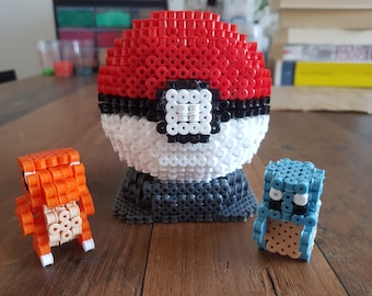 Pokebola hecha de cuentas de hierro en un soporte con charmander y squirtle