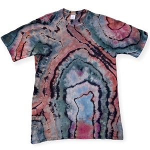 Op de afbeelding: Een tie-dye T-shirt met een draaiende print in zwart, bruin, roze en blauw. Het shirt heeft een ronde hals en korte mouwen.