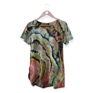 Pode incluir: Uma camisa tie-dye com um padrão de espiral verde, preto e vermelho. A camisa tem mangas curtas e uma gola redonda.