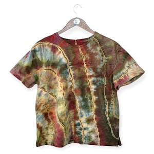 Pode incluir: Uma camiseta tie-dye de manga curta e gola redonda. A camiseta é uma mistura de cores verde, azul, vermelho e amarelo.
