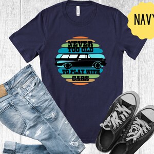 Puede incluir: Camiseta azul marino con un gr&aacute;fico de coche vintage y el texto "Never Too Old To Play With Cars".