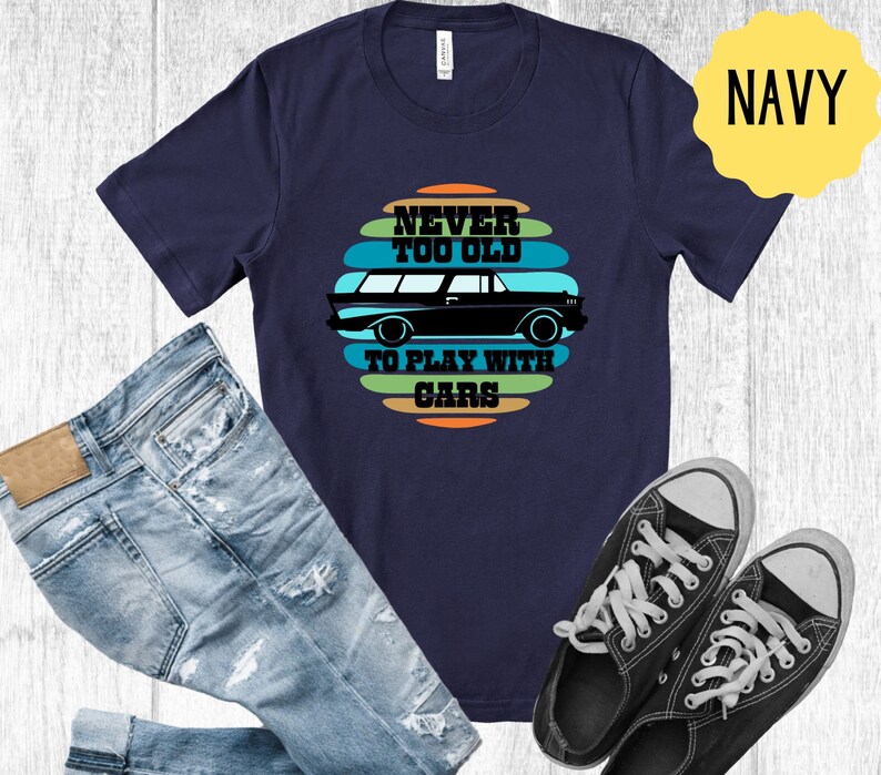 Puede incluir: Camiseta azul marino con un gr&aacute;fico de coche vintage y el texto "Never Too Old To Play With Cars".