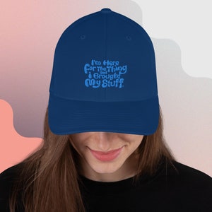 May include: A navy blue baseball cap with the text "I'm here for the thing and I brought my stuff" embroidered in light blue.