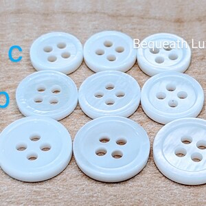 May include: Ten white, round, four-hole buttons with a slightly iridescent finish.  Bequeath Luxury.