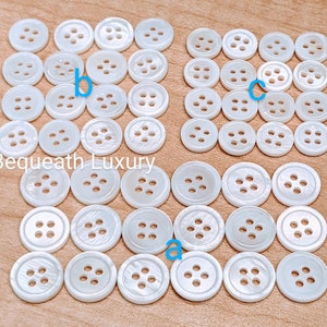 May include: A collection of white mother of pearl buttons with four holes. The buttons are arranged in three groups, labeled a, b, and c.