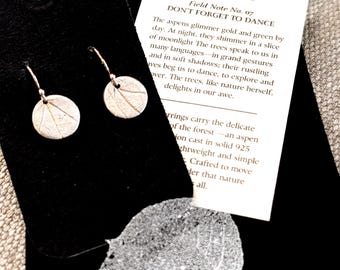 May include: Silver Aspen Imprint Earrings on a black tag. The earrings are round with a leaf imprint. The tag includes the text "ASPEN IMPRINT EARRINGS" and "DON'T FORGET TO DANCE". The earrings are lightweight and simple.