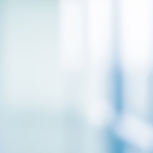 May include: A blurred background image with a light blue and white color scheme. The image is out of focus and appears to be of a room or office space.