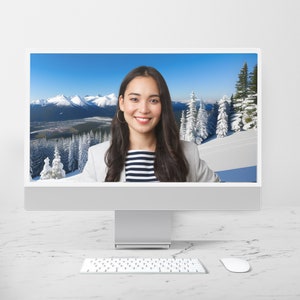 May include: A woman with long dark hair is on a video call. She is wearing a white blazer and a striped shirt. The background is a snowy mountain scene.