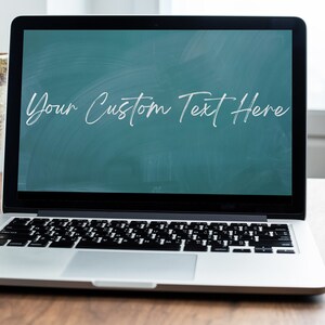 May include: A silver laptop computer with a black keyboard and a green screen that says "Your Custom Text Here". The laptop is sitting on a wooden table.