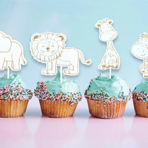 Könnte beinhalten: Sechs Cupcakes mit blauem Frosting und bunten Streuseln, die mit tierischen Cupcake-Toppern verziert sind. Die Topper sind ein Löwe, ein Elefant, eine Giraffe, ein Zebra, ein Affe und ein Vogel.