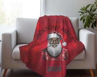 May include: Red fleece blanket featuring a black Santa Claus illustration and the text "Jackson Family Christmas 2023".