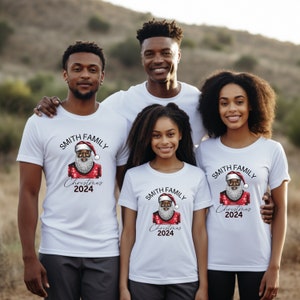 May include: A family of four wearing white t-shirts with a black Santa Claus graphic and the text "Smith Family Christmas 2024".