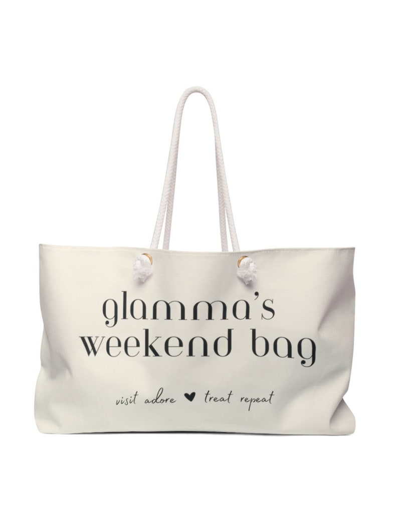 May include: White canvas tote bag with black text that reads "glamama's weekend bag" and "visit adore &hearts; treat repeat".