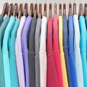 Puede incluir: Veinti&uacute;n sudaderas de diferentes colores colgadas en perchas de madera. Los colores incluyen azul abeto, verde claro, menta calc&aacute;rea, espuma de mar, orqu&iacute;dea, violeta, pimienta, gris, blanco, carmes&iacute;, sand&iacute;a, mantequilla, mezclilla, azul flo, Chambray, azul laguna, azul vaquero y azul marino.