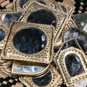 Peut inclure: Une collection de petits miroirs décoratifs avec des cadres dorés. Les miroirs sont de formes variées, rondes, carrées et arquées, et sont présentés dans des paniers tressés. Les cadres ont un design détaillé et pointillé.