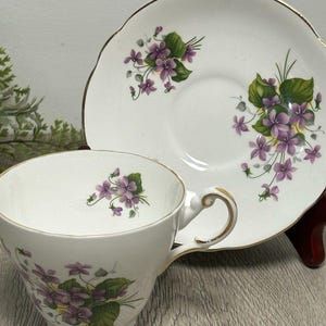 Taza de té y platillo de porcelana inglesa estilo Regency vintage con flores moradas y ribete dorado
