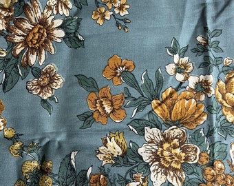 Könnte beinhalten: Ein blauer Stoff mit einem floralen Muster mit gelben, braunen und weißen Blumen. Der Stoff hat den Text "... SCOTCHGARD FINISH" oben aufgedruckt.