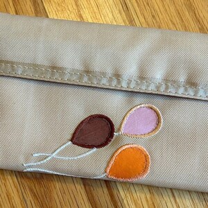Cartera de nailon color canela con bordados de globos de Roger Gimbel Accessories de los años 80