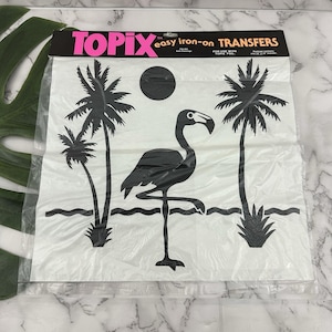 May include: A package of Topix easy iron-on transfers with a black flamingo, palm trees, and sun design. The package is in a clear plastic bag with black and pink text at the top.