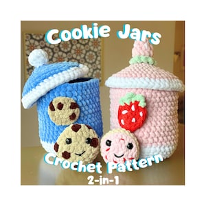 Op de afbeelding: Twee gehaakte koekjespotten, één blauwe en één roze, met witte randen en deksels. De blauwe pot heeft een koekjesapplicatie en de roze pot heeft een aardbeienapplicatie. De tekst "Cookie Jars Crochet Pattern 2-in-1" wordt weergegeven.