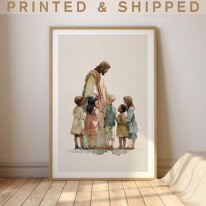 Könnte beinhalten: Ein gerahmter Aquarellkunstdruck mit einer zentralen Figur in einem beigen Gewand, umgeben von fünf Kindern in gedeckter Kleidung. Der Text PRINTED & SHIPPED steht oben. Das Bild verwendet sanfte, neutrale Töne und einen hellen Hintergrund.
