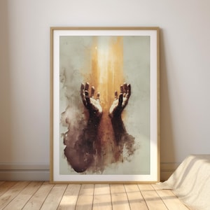 Könnte beinhalten: Gerahmter Kunstdruck mit einer abstrakten Aquarellmalerei von zwei nach oben gerichteten Händen. Das Kunstwerk verwendet eine warme Farbpalette mit Braun-, Orange- und Gelbtönen, die ein Gefühl von Licht und Spiritualität erzeugt. Der Druck ist in einem Holzrahmen.