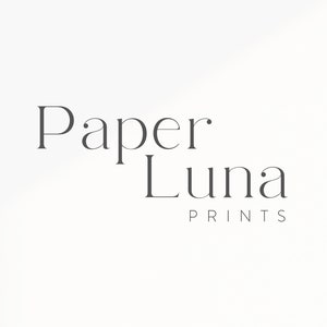 May include: The words "Paper Luna Prints" are displayed in a minimalist, elegant font. The text is in a dark gray color against a white background. The design is simple and clean, suitable for branding or a logo.