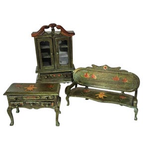 May include: Miniature dollhouse furniture set. The set includes a small cabinet with glass doors, a table with drawers, and a bench. The furniture is painted green with red and yellow floral and teddy bear designs.