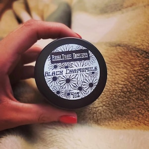 May include: A black jar with a white label that says "Realtree Designs" and "Black Chamomile" with a daisy design. The jar is 4 oz.