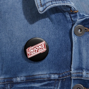 May include: A black button with white text that reads "The Unions Strike Back" in a red box. The text "Star Wars" is below the box in white.