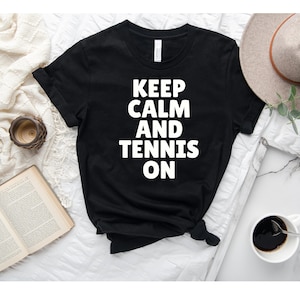 Peut inclure: T-shirt noir avec un texte blanc qui dit "Keep Calm and Tennis On".