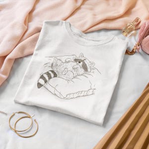 Schlurpi the Raccoon T-Shirt – Cozy Nap | Women’s Organic Cotton Shirt | Sketch-Style Raccoon Illustration