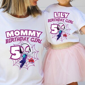 Pu&ograve; includere: Magliette bianche con grafica coordinata. Una maglietta recita "MOMMY BIRTHDAY GIRL" e l'altra "LILY BIRTHDAY GIRL". Entrambe le magliette presentano una grafica a tema ragno con il numero 5 e un disegno a ragnatela.