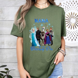 May include: An olive green t-shirt with the word "NANA" in blue, and a graphic of characters from the film Frozen. The phrase "Birthday Girl" is also printed on the shirt.