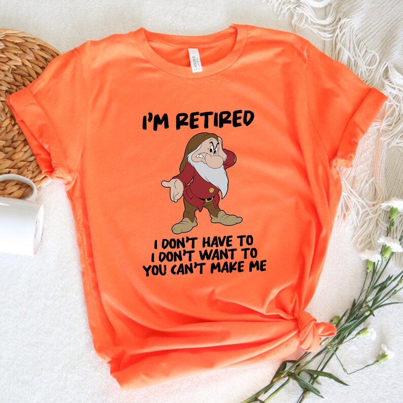 May include: Orange t-shirt with a cartoon image of a grumpy dwarf with a white beard. The text "I'm Retired I don't have to I don't want to You can't make me" is printed on the shirt.