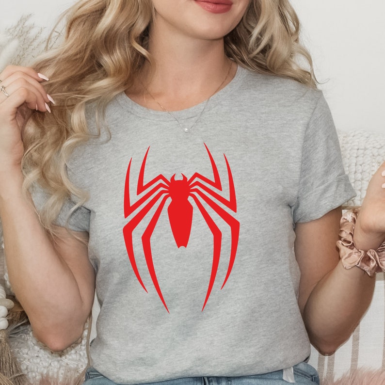 Op de afbeelding: Een grijs T-shirt met een rood Spiderman-logo op de voorkant.