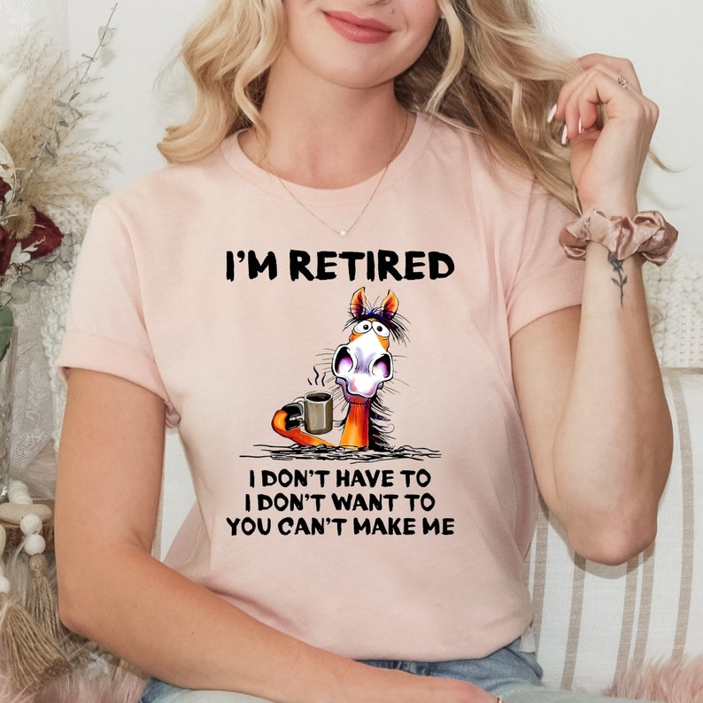 Pu&ograve; includere: Maglietta rosa con un cavallo dei cartoni animati che tiene una tazza di caff&egrave;. Il testo sulla maglietta recita "I'm Retired I don't have to I don't want to You can't make me."
