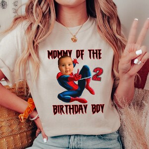 Puede incluir: Una camiseta blanca con el texto "Mommy of the 2 Birthday Boy" en rojo. Una imagen de dibujos animados de Spiderman con la cara de un beb&eacute; superpuesta sobre su cabeza est&aacute; en el centro de la camiseta.