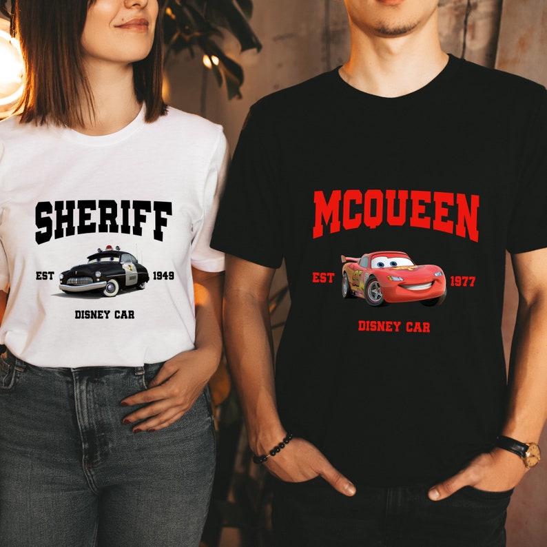 Peut inclure: Deux t-shirts sur le th&egrave;me de Cars de Disney. Le t-shirt blanc pr&eacute;sente une voiture de police noire et blanche avec le texte "Sheriff Est 1949 Disney Car". Le t-shirt noir pr&eacute;sente une voiture de course rouge avec le texte "McQueen Est 1977 Disney Car".