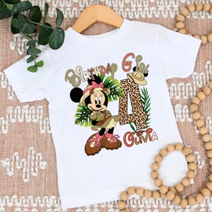 May include: White t-shirt with a cartoon image of a safari-themed Minnie Mouse, a leopard print number four, and the text "Birthday Girl Olivia".
