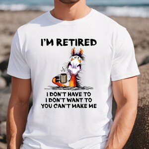 Pu&ograve; includere: Maglietta bianca con un cavallo di cartone animato che tiene una tazza di caff&egrave;. Il testo sulla maglietta recita "I'm Retired I don't have to I don't want to You can't make me."