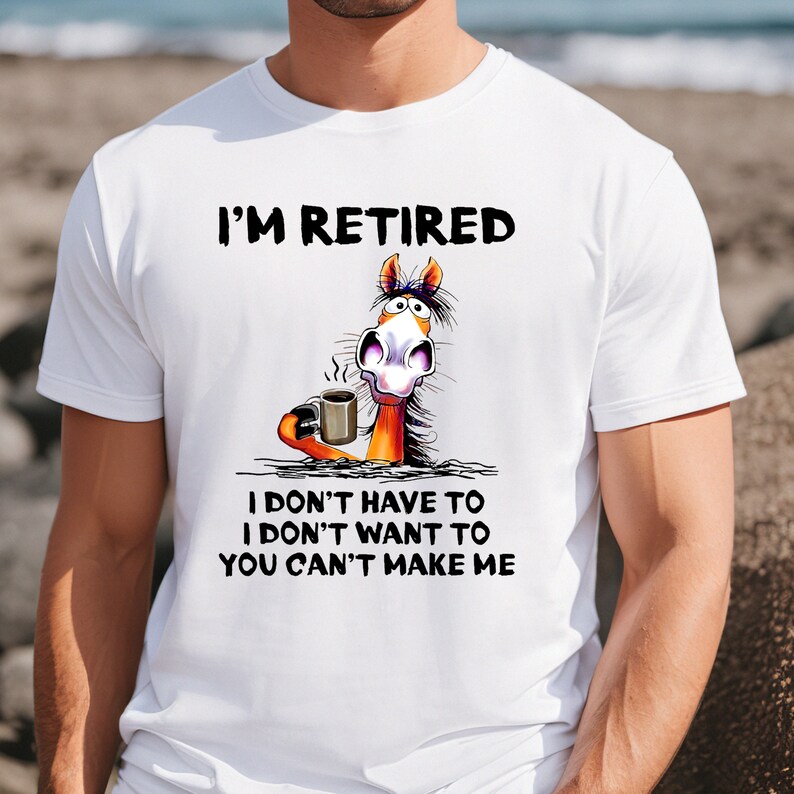 Pu&ograve; includere: Maglietta bianca con un cavallo di cartone animato che tiene una tazza di caff&egrave;. Il testo sulla maglietta recita "I'm Retired I don't have to I don't want to You can't make me."