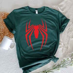 Op de afbeelding: Een donkergroen T-shirt met een rood Spiderman-logo op de voorkant.
