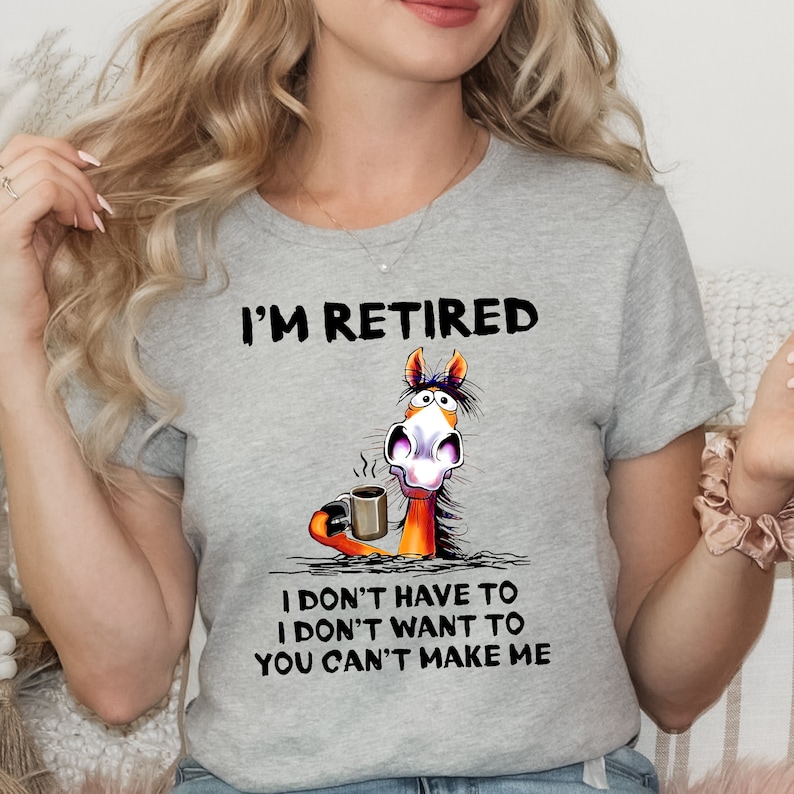 Pu&ograve; includere: Maglietta grigia con un cavallo dei cartoni animati che tiene una tazza di caff&egrave;. Il testo sulla maglietta recita "I'm Retired I don't have to I don't want to You can't make me."