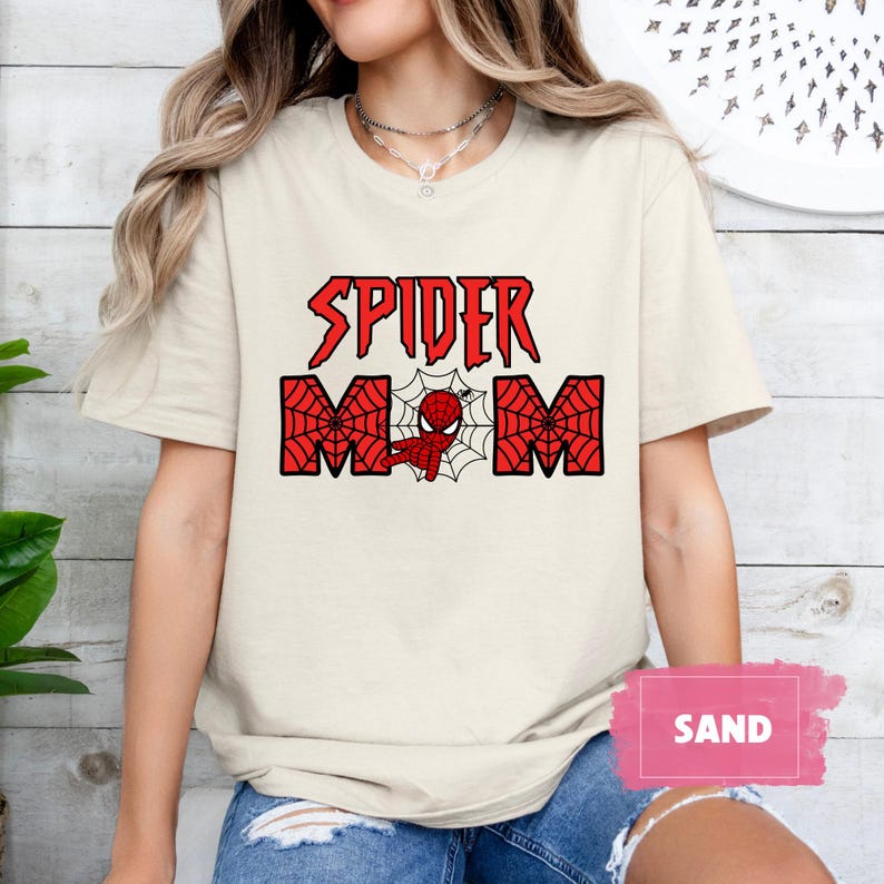 May include: A white t-shirt with a red and black graphic that says "Spider Mom" with a cartoon image of Spiderman in the middle of the word "Mom".