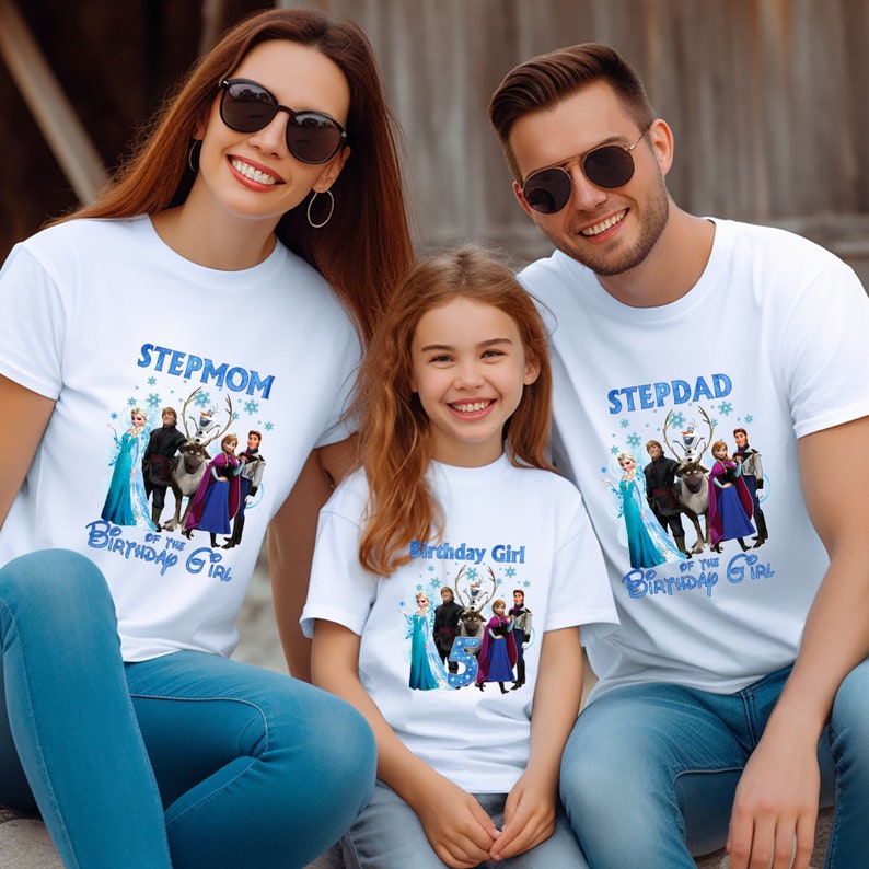 May include: Three people wearing white t-shirts with a blue graphic featuring characters from the movie Frozen. The shirts read "Stepmom of the Birthday Girl", "Birthday Girl", and "Stepdad of the Birthday Girl". The family is smiling.