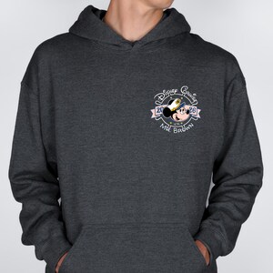 Op de afbeelding: Donkergrijze hoodie met een Disney Cruise-ontwerp. Het ontwerp bevat Mickey Mouse met een kapiteinshoed, de woorden "Disney Cruise" en "2026", en de naam "Mr. Brown". De hoodie heeft een voorzak en een capuchon met trekkoord.